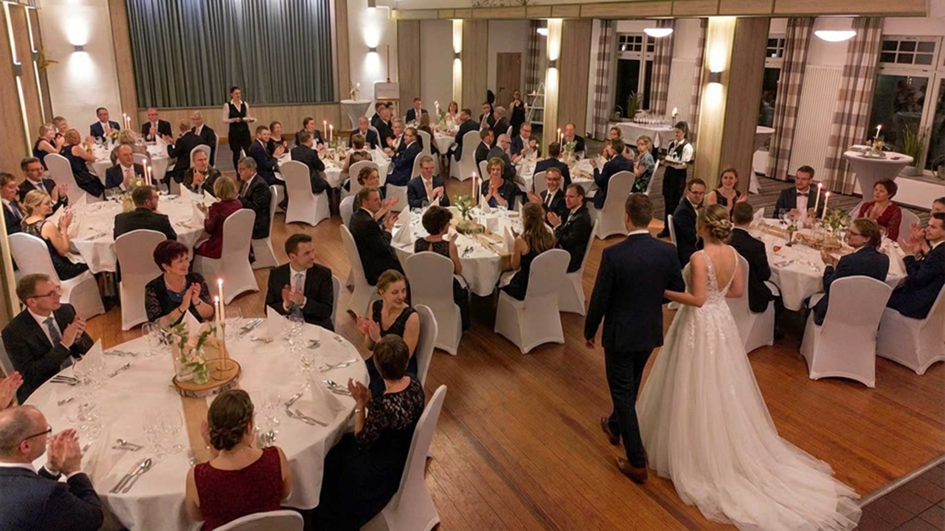Hochzeit im Festsaal des Hotel & Restaurant am Huntepadd in Dötlingen mit Brautpaar beim Einzug und festlich gedeckten Tischen